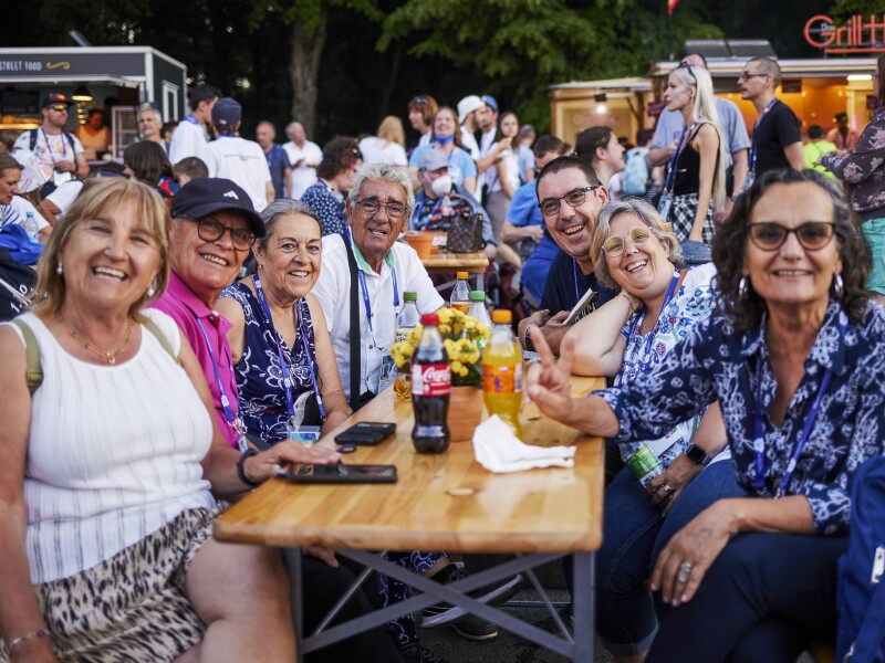 The photo shows a group of people sitting together at a table and smiling joyfully. It is the family of an athlete who has arrived for the National Games.