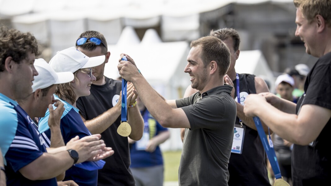 Das Foto zeigt den ehemaligen Fußballer Philipp Lahm während er bei den Nationalen Spielen Berlin 2022 Medaillen an Athlet*innen überreicht. Er hat dabei ein lächeln auf dem Gesicht.