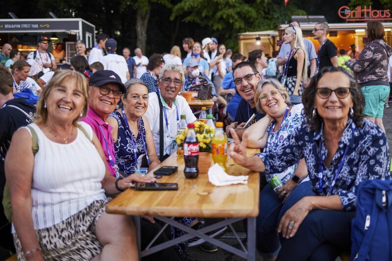 Das Foto zeigt eine Gruppe Menschen, die an einem Tisch beisammen sitzen und freudig lächeln. Es ist die Familie eines Athleten, die zu den Nationalen Spielen angereist ist.