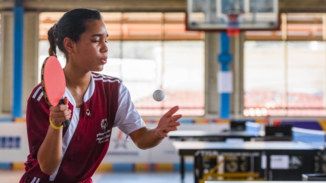 Das Foto zeigt eine junge Sportlerin beim Tischtennis. Sie atmet tief durch und ist dabei, ihren Aufschlag durchzuführen.