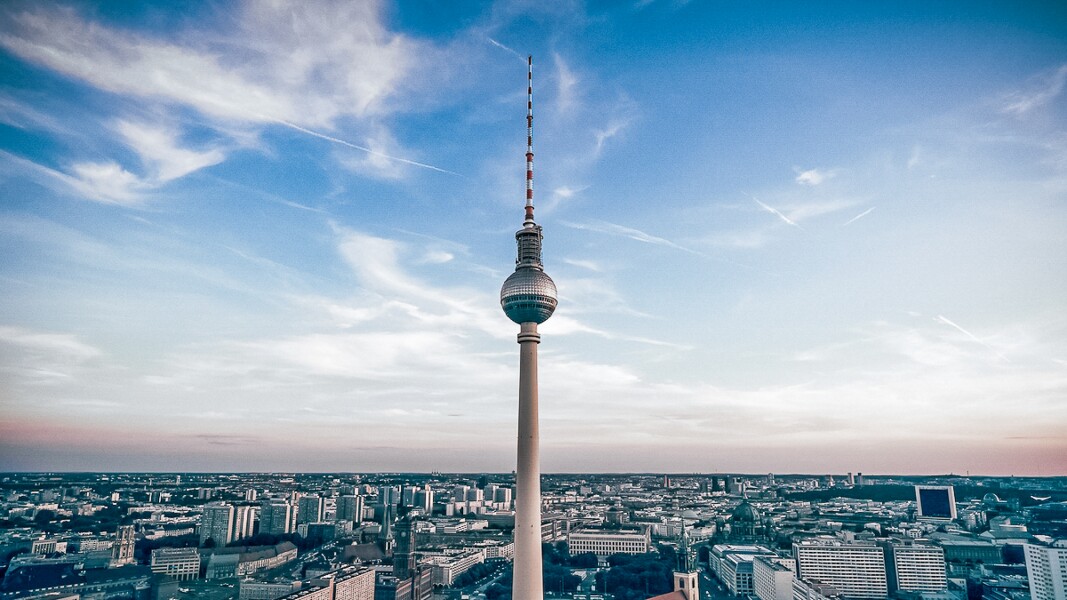 Das Foto zeigt den Berliner Fernsehturm vor dem Panorama der Stadt und vor einem malerischen, blauen Himmel.
