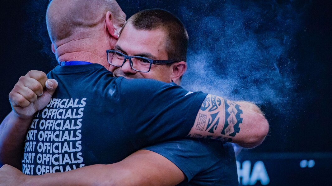 The photo shows a sports official and an athlete embracing.
