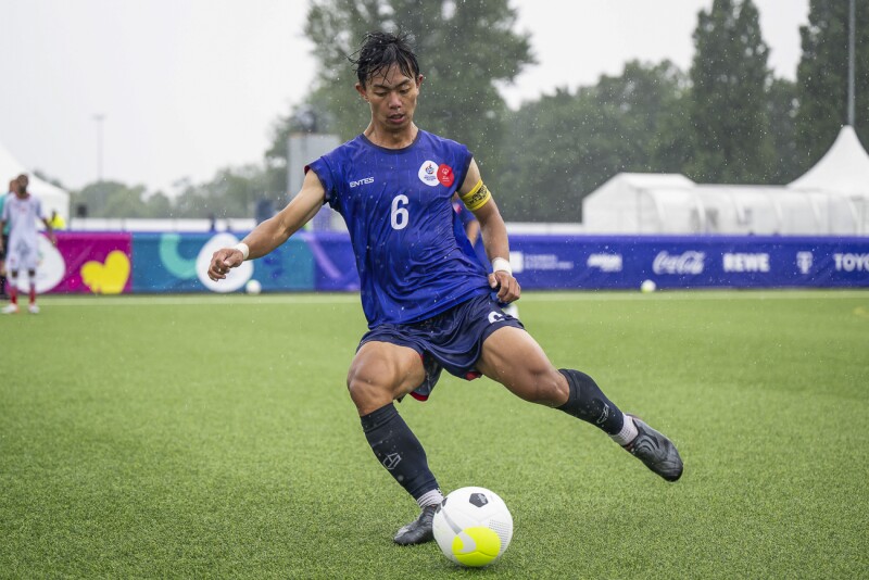 In the photo you can see a futsal player in action. He shoots the ball and it is clearly raining har