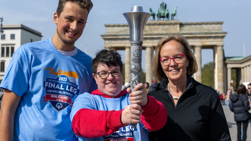 Auf dem Foto sind Athlet*innen und Christiane Krajewski zu sehen. Sie präsentieren freudig die Flacke.