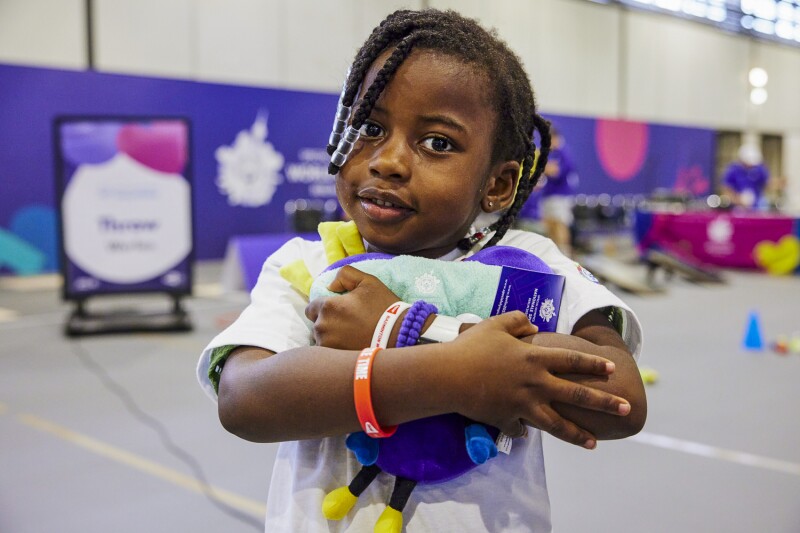 The photo shows a little girl who participated in the Young Athletes program during the World Games in Berlin, holding a plush Unity in her arms.