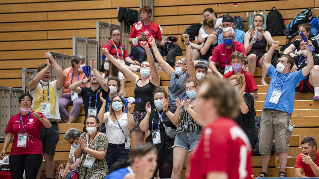 Auf dem Foto sind die Zuschauer*innen beim Handball zu sehen, die während der Special Olympics Nationalen Spiele Berlin 2022 Spaß haben und mit hochgerissenen Armen jubeln.