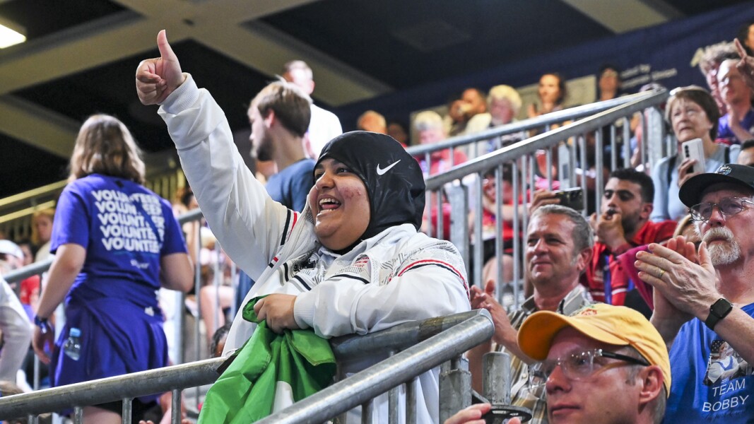 A lady in the stands supporting her team in the powerlifting competition showing thum-ups