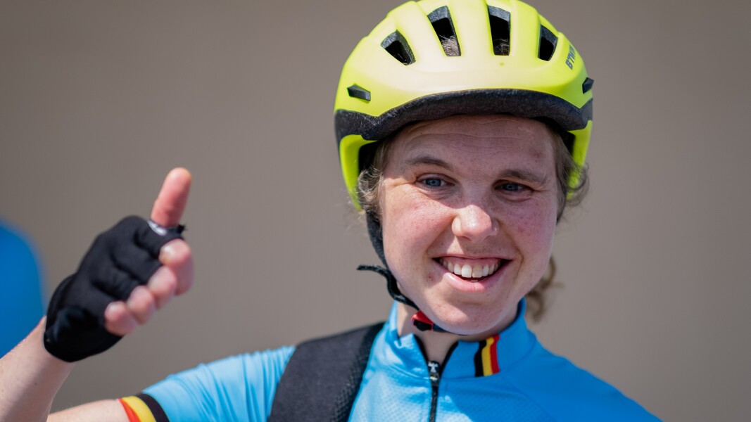 Das Foto zeigt eine Radsportlerin in Nahaufnahme. Sie trägt einen Helm und reckt den Daumen nach oben.