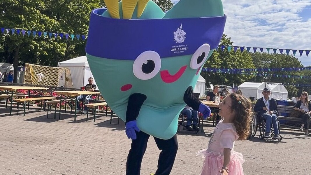 Auf dem Foto ist ein kleines Mädchen zu sehen. Sie lacht unser Maskottchen Unity an und freut sich riesig.