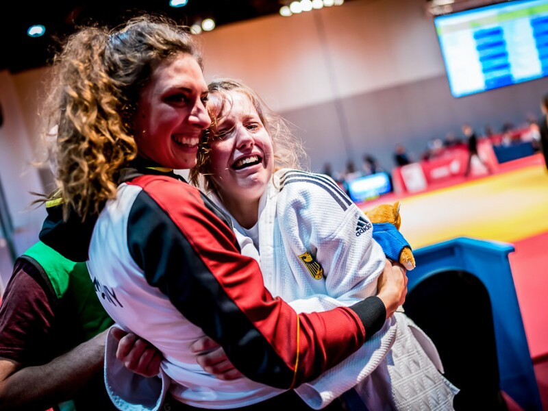 The photo shows a judo athlete lying in the arms of her friend and crying with joy.