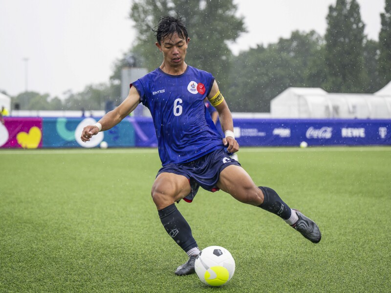 In the photo you can see a futsal player in action. He shoots the ball and it is clearly raining har