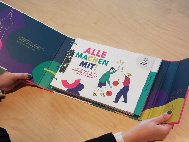 Auf dem Foto hält eine Person das Lehr- und Lernmaterial mit dem Titel "Alle machen mit!" in den Händen.