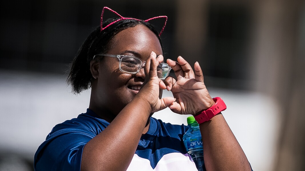 Auf dem Foto ist eine Athletin zu sehen, die mit ihren Händen ein Herz formt.