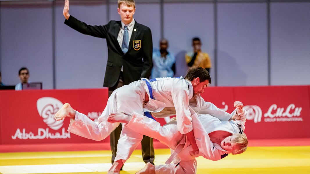 Das Foto zeigt zwei Judoka auf der Matte und einen Kampfrichter.
