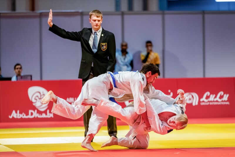 Das Foto zeigt zwei Judoka auf der Matte und einen Kampfrichter.