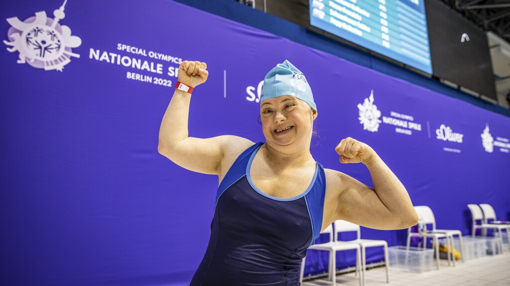 The photo shows athlete Anna Wyrzgol from Special Olympics Lower Saxony. She is happy, raises her arms and smiles at the camera.