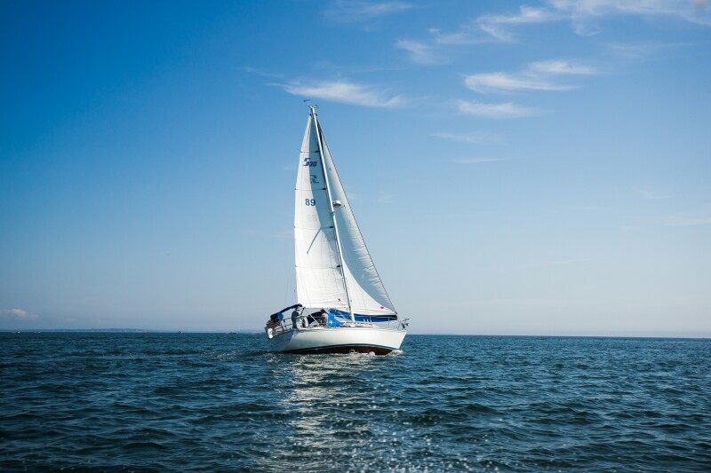 A picturesque image of a sailboat on the water and against a blue sky. 