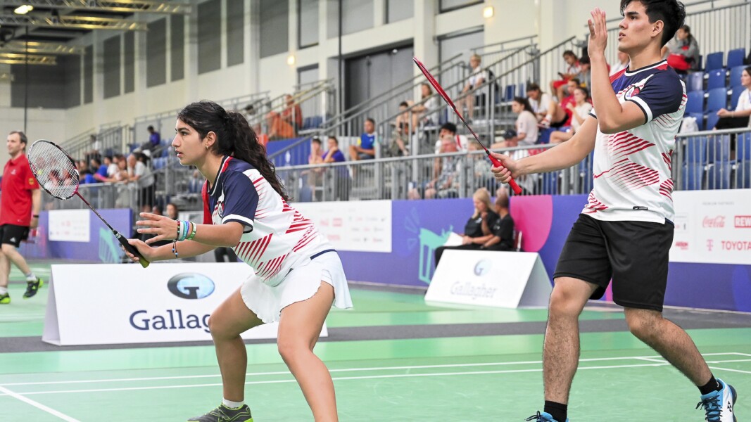 Auf dem Foto sind zwei Athlet*innen beim Badminton-Mix zu sehen.Beide sind in Position und warten auf den Ball.