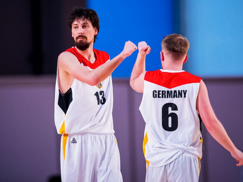Zwei Basketballspieler geben sich auf dem Spielfeld gegenseitig die Faust, um abzuklatschen.
