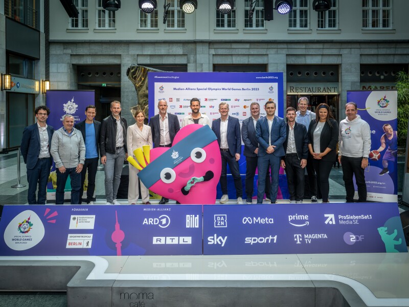 Auf dem Foto sind Vertreter der Medien-Allianz zu sehen und das Maskottchen Unity.