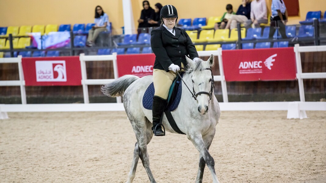The photo shows an athlete during her equestrian performance on her white horse.