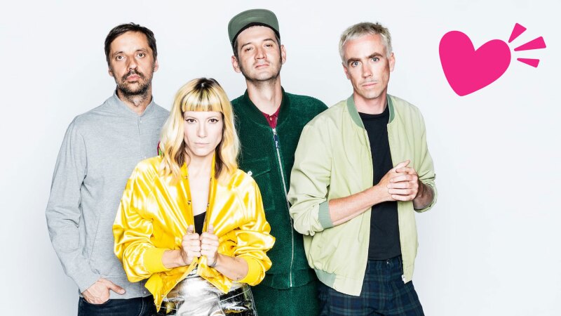 The photo shows the Berlin cult band MiA., which will perform at the Opening Ceremony of the National Games. The four band members are looking at the camera. In the corner is additionally placed a pink heart. 