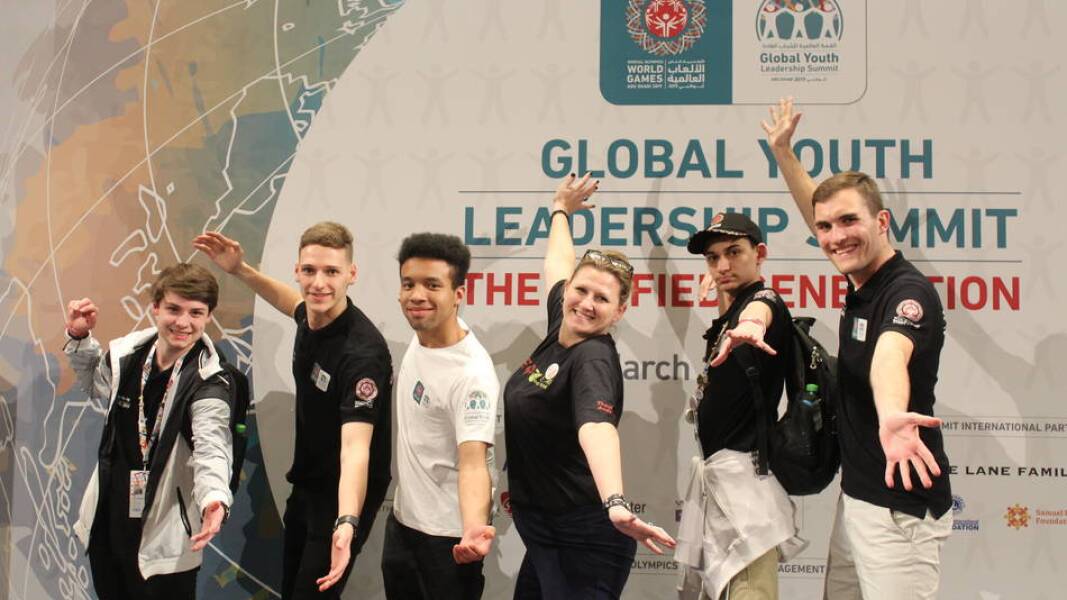 Auf diesem Foto sind mehrere junge Leute beim GYLS zu sehen. Sie strecken die Arme aus und schauen freudig