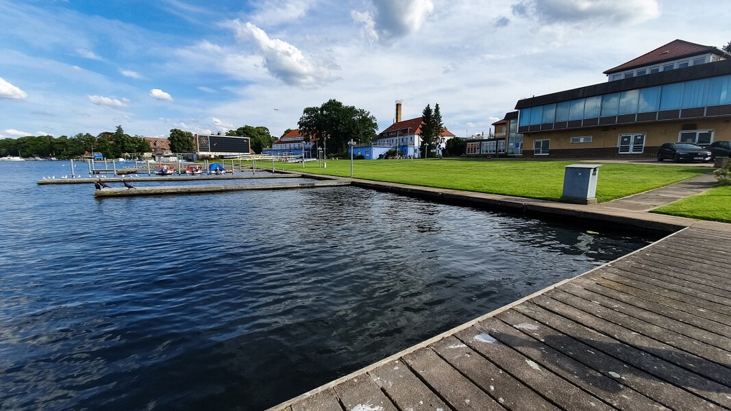 Das Foto zeigt mehrere Stege die ins Wasser reichen und im Hintergrund einige kleinere Gebäude.