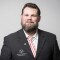 Das Foto ist ein Portrait von Mark Solomeyer, Nationaler Athletensprecher und Vizepräsident von Special Olympics Deutschland. Er trägt einen schwarzen Anzug und lächelt in Richtung Kamera.