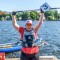 Das Foto zeigt die Kanutin Juliana Rößler nach ihrem Gewinn im Kanurennen während der Special Olympics Nationalen Spiele Berlin 2022. So hält jubelnd ihr Paddel über dem Kopf hoch.