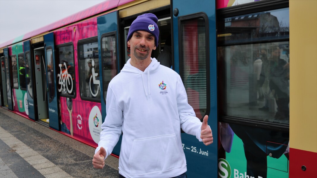 The photo shows Robert Herberg in front of the stickered S-Bahn. He is giving the thumbs up and smiling.