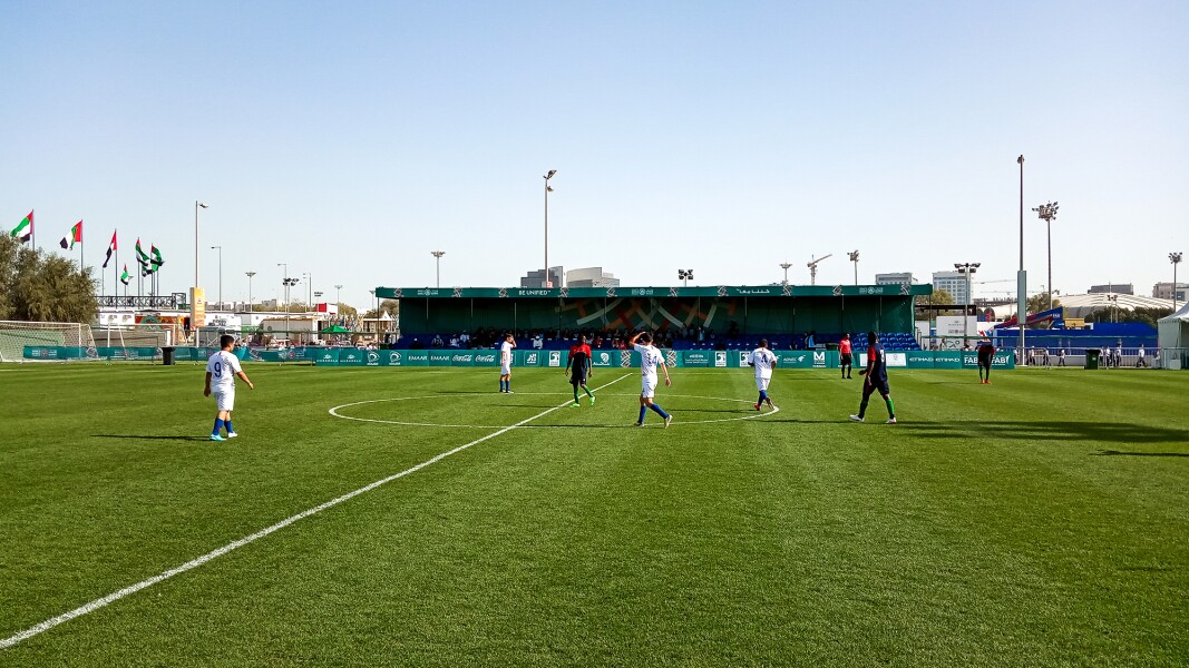 Das Bild zeigt ein Futsal-Spiel im Freien aus der Weitsicht. Das Spiel findet auf Rasen statt.
