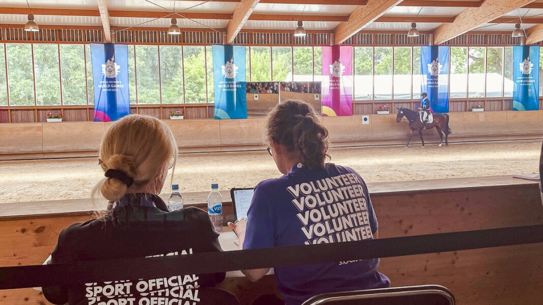 The photo shows Sport Officals and volunteers at Equestrian.  Concentrated they watch the action.