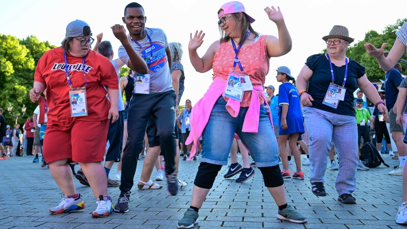 Auf dem Foto tanzen vier Athletinnen und Athleten ausgelassen und freuen sich. Im Hintergrund tanzen noch weitere Feiernde.