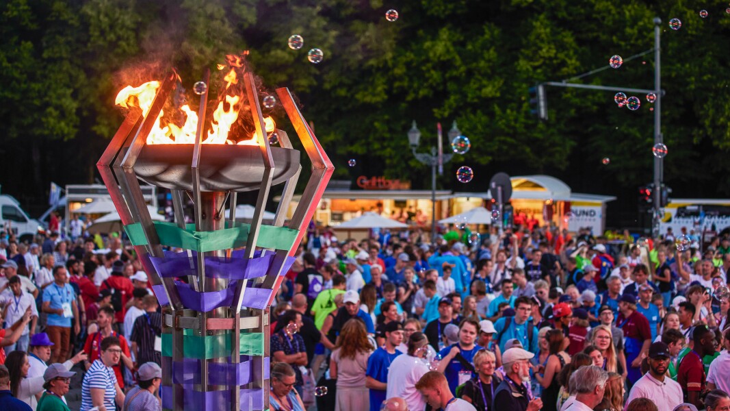 Auf dem Foto ist die brennende Flamme der Hoffnung von Special Olympics zu sehen und einige Seifenblasen, die in der Luft umher fliegen. Im Hintergrund sind die feiernden Athletinnen und Athleten gemeinsam mit anderen Aktiven der Nationalen Spiele zu sehen.