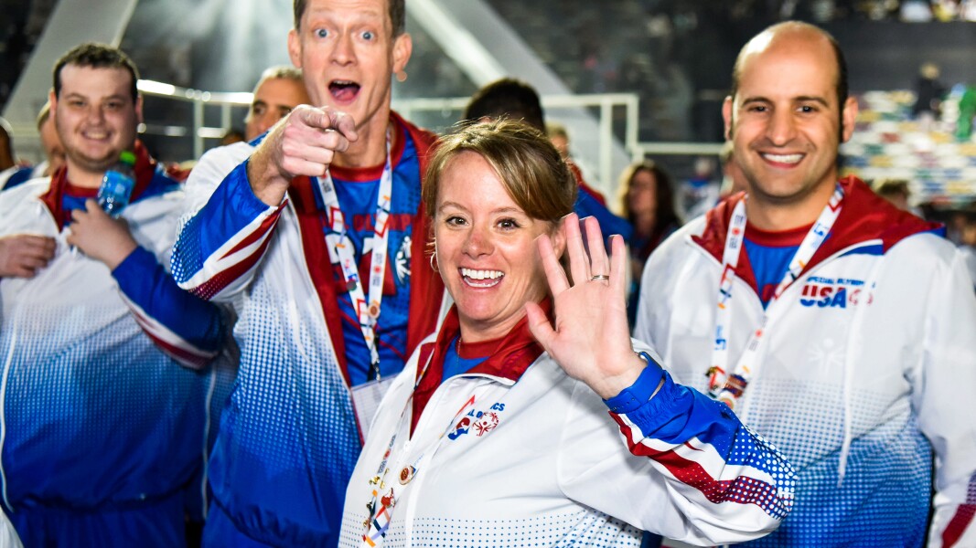 Auf dem Foto sieht man Athleten der amerikanischen Delegation. Sie winken in die Kamera.