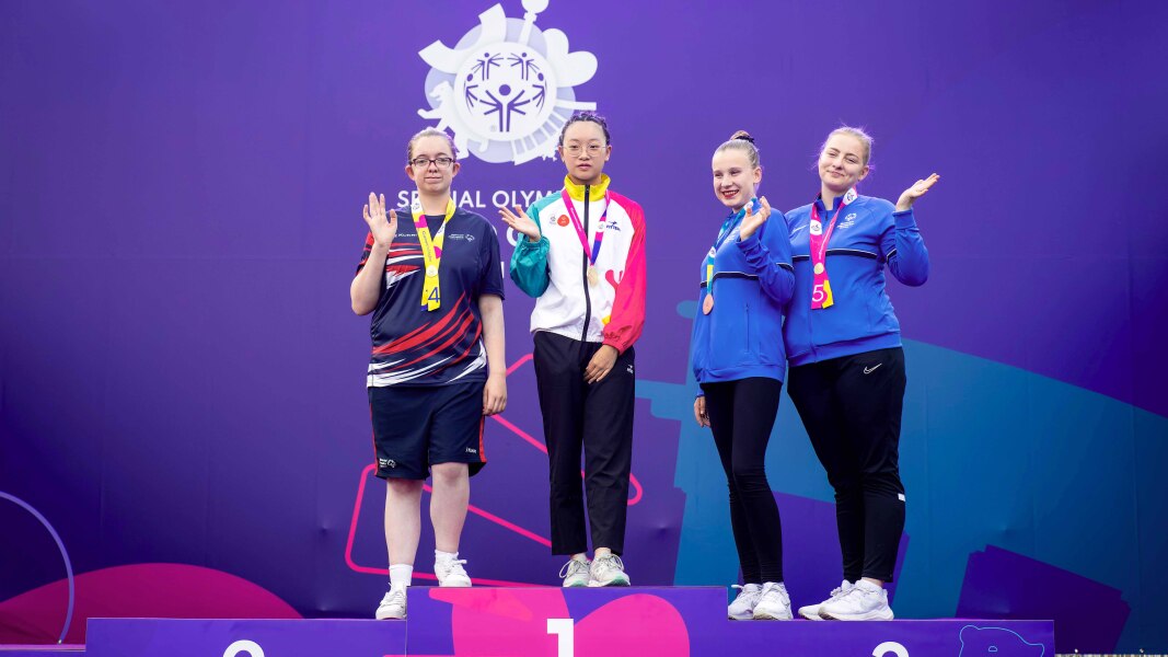 Four people posing to the camera celebrating their success in gymnastics-rhythmic during the awards ceremony.