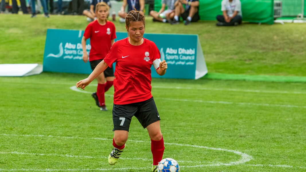 Das Foto zeigt zwei Sportlerinnen beim Futsal. Die vordere Spielerin dribbelt mit dem Ball.