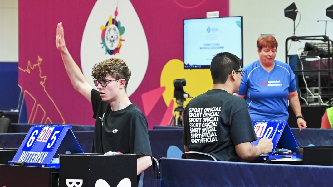 Auf dem Foto sind zwei Schiedsrichter der Games 2023 zu sehen. Sie sitzen hinter der Punktevergabe.