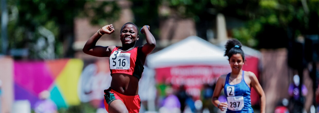 The photo shows two athletes on the track field, one jumping out of joy after finishing the competition first.