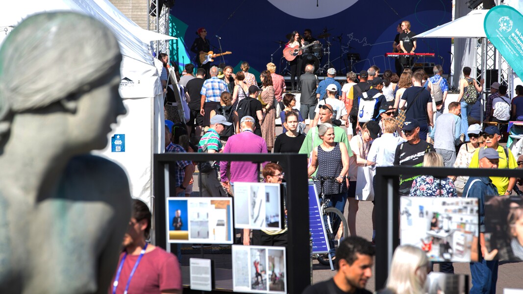 The photo shows a scene during the Special Olympics Festival 2022. Many people are crowding around the booths and in front of the stage where a band is performing.