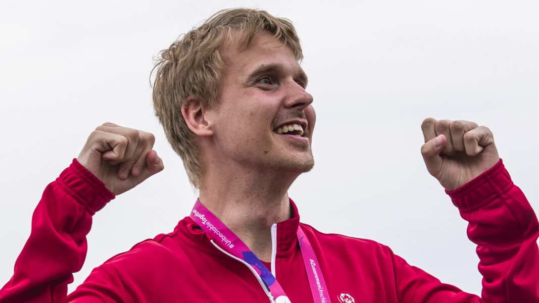 Das Foto zeigt Kai-Jürgen Pönisch von TeamSOD nachdem er seine Goldmedaille im Freiwasserschwimmen bekommen hat. Er hat die Arme erhoben und jubelt lächelnd.