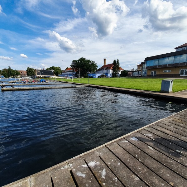 Das Foto zeigt mehrere Stege die ins Wasser reichen und im Hintergrund einige kleinere Gebäude.