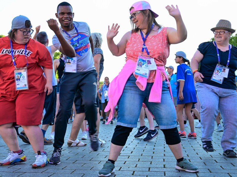 Auf dem Foto tanzen vier Athletinnen und Athleten ausgelassen und freuen sich. Im Hintergrund tanzen noch weitere Feiernde.