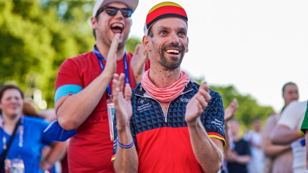 On the photo you see two men who smile hearty and clap their hands.