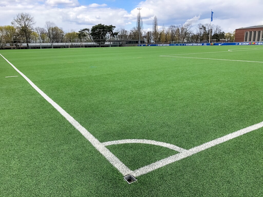 Das Foto zeigt ein Fussballfeld und seine weißen Markierungen. Der Fokus liegt auf einer Ecke.