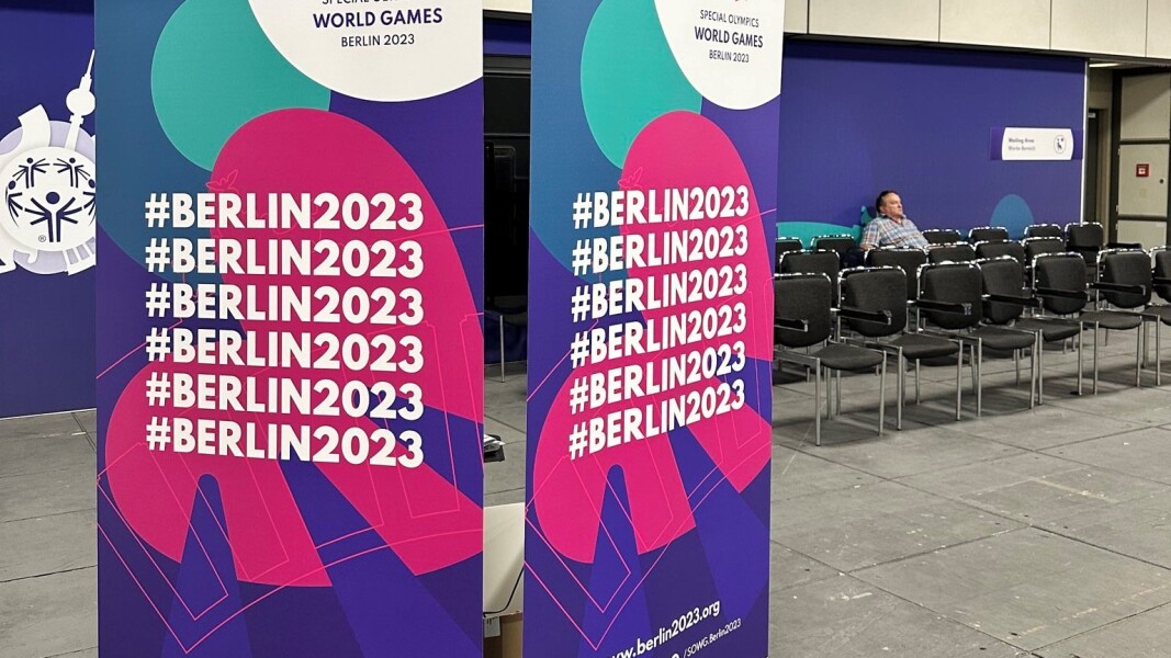 Das Bild zeigt den Eingangsbereich des UDAC. Im Hintergrund sind Wartestühle zu sehen, während vorn ein großer Werbeaufsteller in den Farben und mit dem Logo der Berlin 2023 Games steht.