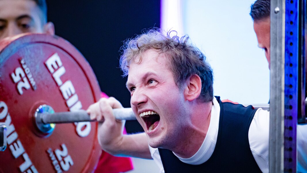 Das Foto zeigt einen Athleten beim Kreuzheben. Er strengt sich an und schreit.