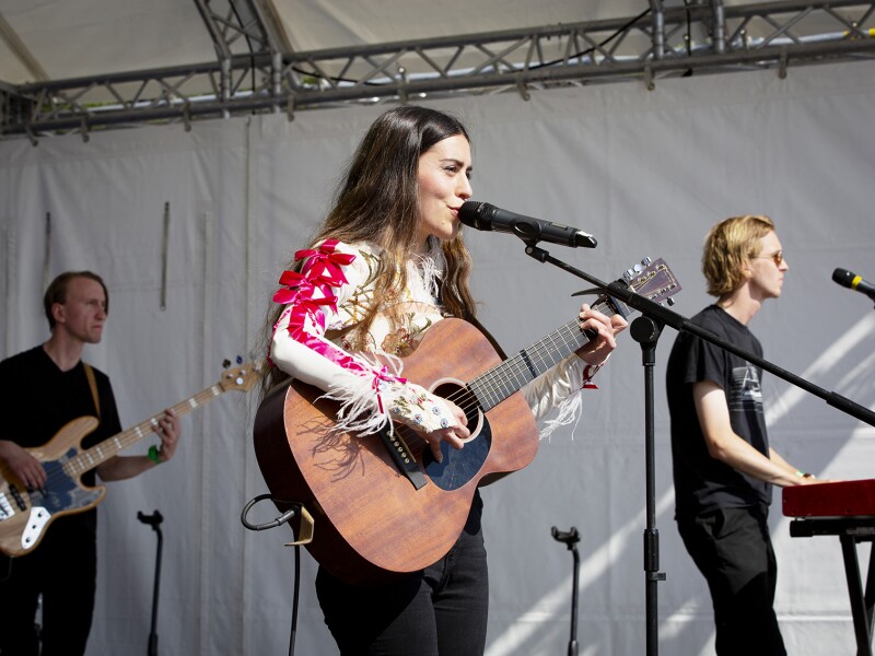 Das Foto zeigt eine Band, die auf dem Special Olympics Festival 2022 auftritt. Im Vordergrund ist die Sängerin zu sehen, die mit ihrer Gitarre auf der Bühne steht.