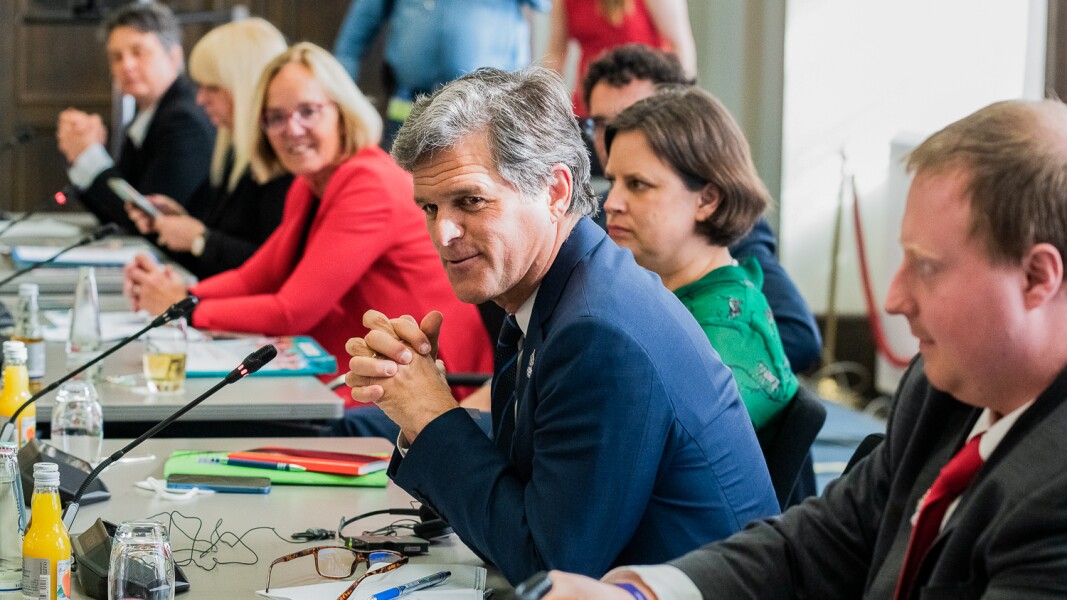 Auf dem Foto ist ein Ausschnitt der Sitzung des Weltspielekomitees zu sehen. Im Fokus ist Timothy Shriver, aber neben ihm sitzen noch weitere Menschen.